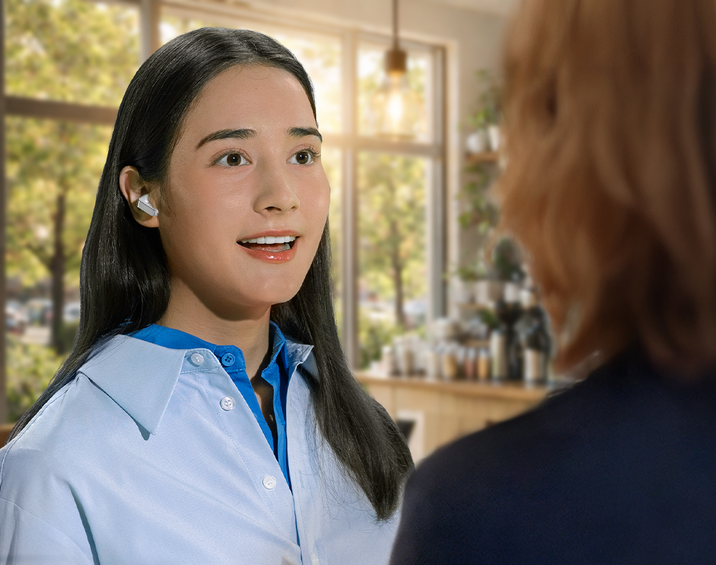 画面中，一位女士佩戴映雪白Galaxy Buds4 Pro耳机正与他人交谈，生动展现出其智能语音检测功能。