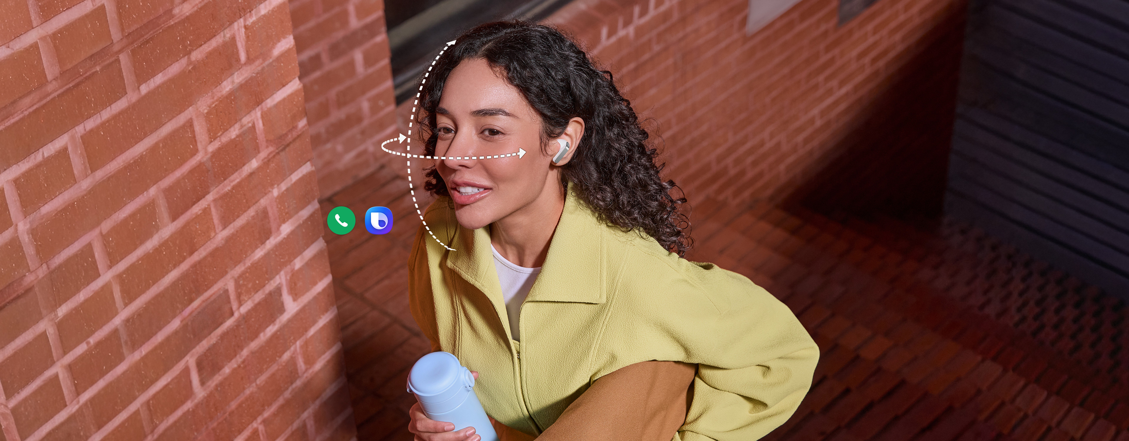 画面中，一位佩戴着Galaxy Buds4 Pro耳机的青年，一手端着简约随行杯，另一只手则提着一个手提包。由虚拟线条构成的垂直与水平网格环绕在她的面部，展现出Galaxy Buds4 Pro耳机所支持的头部动作交互功能。画面展示了通话应用程序图标与Bixby应用程序图标上的动作标识，表明用户可通过头部动作交互功能运行这两个应用程序。