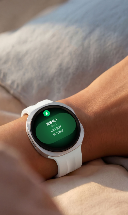 画面中，一个身影安睡于床榻，其腕间佩戴着一块Galaxy Watch9。画面呈现了一块Galaxy Watch9，设备屏幕弹出睡眠跟踪功能界面；佩戴者嘴角噙着浅淡笑意，直观传递出睡眠指导功能有效优化其睡眠模式与作息习惯，带来修复力更佳的深度休憩体验。