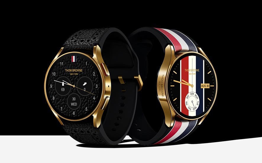 两款Galaxy Watch6蓝牙版 40mm，一款搭配黑色卵石纹皮革表带，另一款搭配经典罗缎饰配色的光滑皮革表带。黑色卵石纹皮革表带与黑色、金色表盘相融合，标志性罗缎丝带红白蓝色表带和Thom Browne的主题壁纸相融合。