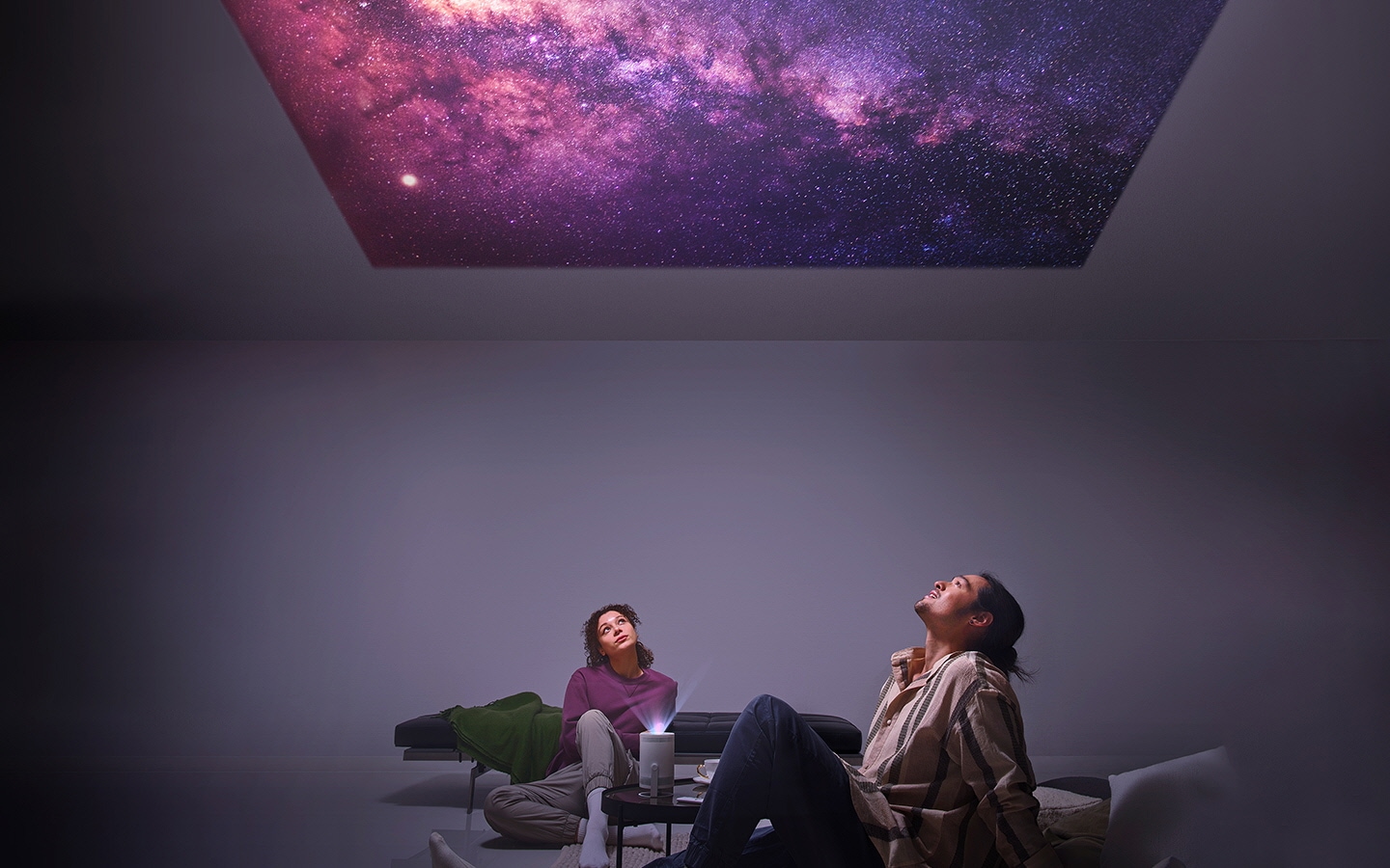 一对男女凝视着投影仪投影到天花板上的星星。
