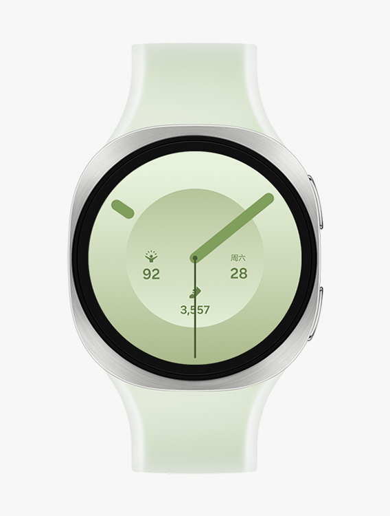 搭配绿色雾面表带的 Galaxy Watch9，展示正面视图与斜向特写视图，表盘可显示时间、精力评分、日期以及步数等信息。