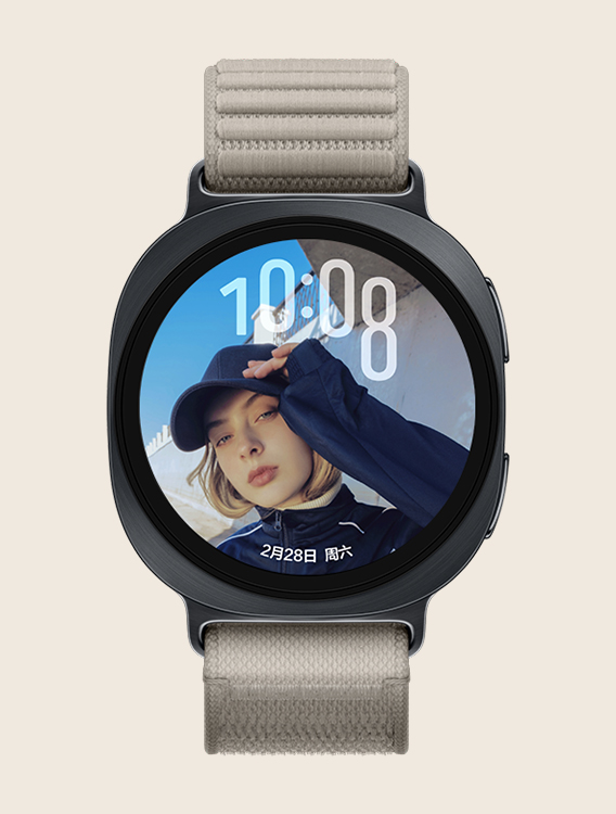 配备棕色织物表带的 Galaxy Watch9，展示正面视图与斜向特写视图；手表搭载自定义人像表盘，时间显示在表盘上方，日期显示在下方，文字信息不会遮挡人像面部。